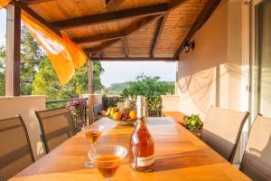 Villa Emily Zakynthos في تسيليفي: زجاجة من النبيذ على طاولة خشبية مع كأسين