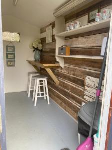 Habitación con pared de madera, taburete y barra. en Hopgarden Glamping - Luxury 6m bell tent, en Wadhurst