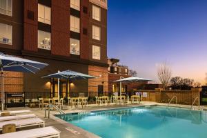 a pool with chairs and umbrellas next to a building at Crowne Plaza North Augusta, by IHG in North Augusta
