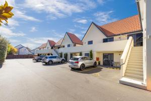 una fila de casas con autos estacionados en un estacionamiento en Bella Vista Motel & Apartments Christchurch, en Christchurch