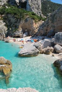 een groep mensen op een strand met rotsen bij Villa Maddalena in Baunei