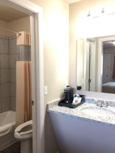 a bathroom with a sink and a toilet and a mirror at Downtown Motel Woodward in Woodward