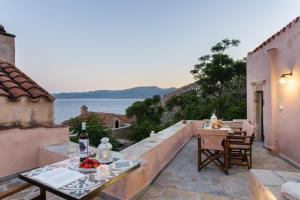 a patio with a table and chairs and a view of the water at Myrsini's Castle House - Comfortable Residence with Large Balcony & Sea View in Monemvasia