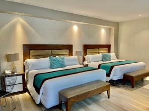 a hotel room with two beds with blue pillows at Áurea Hotel and Suites in Guadalajara
