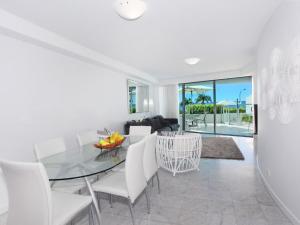 a dining room with a glass table and white chairs at Sirocco 202 in Mooloolaba