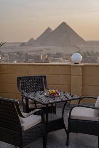 een tafel en stoelen op een balkon met piramides bij Gardenia Pyramids view inn in Caïro