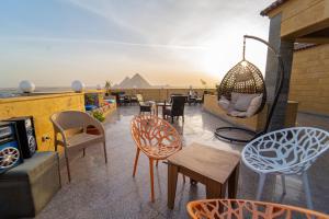 een dakterras met stoelen en tafels met piramides op de achtergrond bij Gardenia Pyramids view inn in Caïro