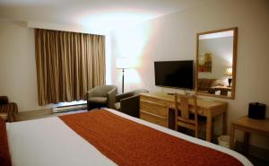 a hotel room with a bed and a desk and a television at Auberge du Grand Lac in Magog-Orford