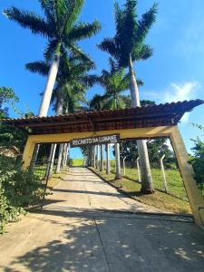 une porte menant à la plage sur une route bordée de palmiers dans l'établissement Pousada Recanto da Lunane, à Barra do Piraí