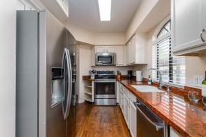 uma cozinha com armários brancos e electrodomésticos de aço inoxidável em Villa Comfort condo em Scottsdale