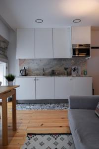 a kitchen with white cabinets and a wooden floor at Aurora Garden in Porto