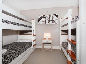 a bedroom with two bunk beds and a desk at Oceans 201 luxurious beachfront apartment in Mooloolaba