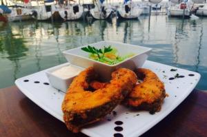 a plate with fried onion rings and a bowl of salad at Silver Side Apartments in Siófok
