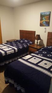 a bedroom with two beds and a table with a lamp at Hotel Centric Chihuahua in Chihuahua