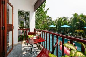 einen Balkon mit einem Tisch und Stühlen neben einem Pool in der Unterkunft Hoi An Riverside Villas & Apartments in Hoi An