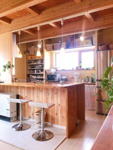 a kitchen with a wooden counter and stools at 毎日が休日 guest house in Aizuwakamatsu