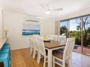 uma cozinha e sala de jantar com uma mesa de madeira e cadeiras em Surfspray I Pet Friendly I Absolute Beachfront em Culburra Beach