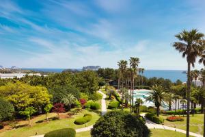 a view of a park with a fountain and the ocean at Kensington Resort Seogwipo in Seogwipo