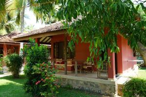 ein kleines rotes Haus mit einem Tisch im Hof in der Unterkunft Puetz Travels Beach Resort in Wayikkal