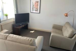 uma sala de estar com um sofá e uma televisão em 'The Rockingham' 4 double beds, Netflix TVs, WIFI, parking em Corby