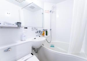 bagno bianco con lavandino e doccia di APA Hotel Ginza Shintomicho Ekimae Kita a Tokyo