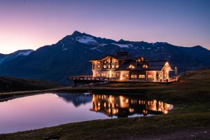 a house on a lake in front of a mountain at Sunny Valley Mountain Lodge in Bormio