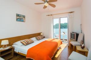 1 dormitorio con 1 cama con manta naranja y ventana en Villa Malfi, en Zaton