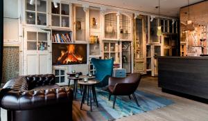 a living room with a couch and chairs and a fireplace at Motel One Amsterdam-Waterlooplein in Amsterdam