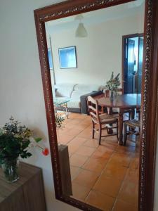 uno specchio che riflette un soggiorno con tavolo e divano. di Acogedor duplex a 15min de Marbella a Monda