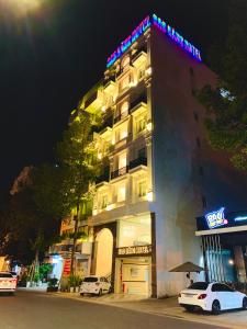 un bâtiment d'hôtel avec des voitures garées devant lui dans l'établissement SAO BĂNG HOTEL, à Thu Dau Mot