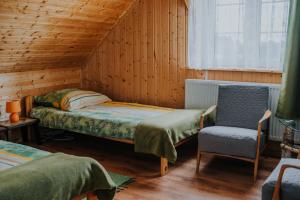 een slaapkamer met een bed, een stoel en een raam bij Dom Gościnny Sowia Stópka in Miłomłyn +62 foto's