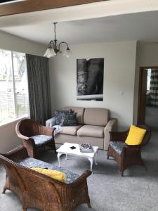 a living room with a couch and chairs and a table at Fitzroy Gem in New Plymouth