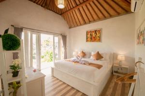 a bedroom with a large white bed and a window at kaje cottage & restaurant in Nusa Penida