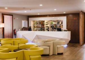 a bar with yellow chairs and a white counter at Hotel Fonte Velha in Ponte da Barca