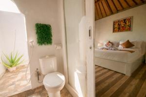 a bathroom with a toilet and a bed in a room at kaje cottage & restaurant in Nusa Penida