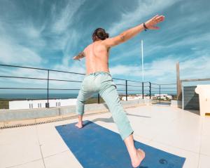 een man die op een dak sprong bij HI Arrifana Destination Hostel in Aljezur