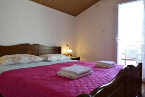 a bedroom with a pink bed with towels on it at Apartment Tommy in Malinska