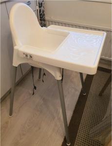 a white high chair sitting in a room at Homely Apartment MILA in Kotka