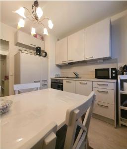 a kitchen with white cabinets and a table with chairs at Homely Apartment MILA in Kotka