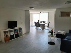 a living room with a television and a table with chairs at Haus Melchaazopf in Giswil