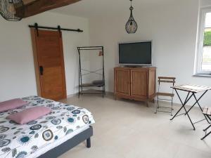 a bedroom with a bed and a flat screen tv at La Clef des Champs in Potelle