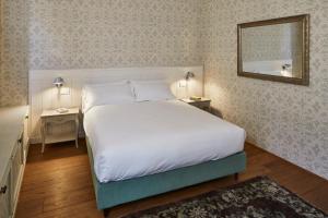 a bedroom with a large white bed and a mirror at Casa Gugù in Ravenna