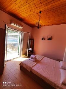 een slaapkamer met een bed en een groot raam bij Fabulous apt. w/breakfast near the sea! in Sivota