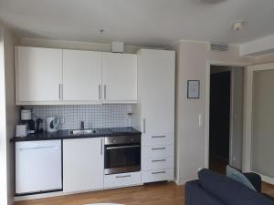 cocina con armarios blancos y sofá azul en Veversmauet Apartments en Bergen