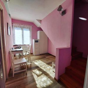 a pink room with a staircase and a table and chairs at Foresteria Villa Simona in Colico