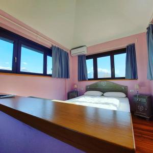a bedroom with a large wooden bed with windows at Foresteria Villa Simona in Colico