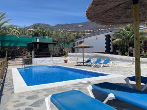 a swimming pool with two chairs and an umbrella at Finca Pozo Taburiente in El Paso