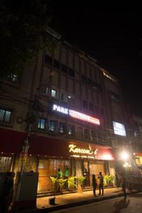 een gebouw waar mensen 's nachts buiten staan bij HOTEL PARK VICTORIA in Calcutta