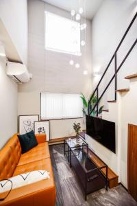 un soggiorno con divano arancione e TV di Ken's Place Azabudai a Tokyo