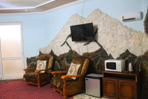 a living room with two chairs and a tv on a wall at Hotel Bashnya in Kislovodsk